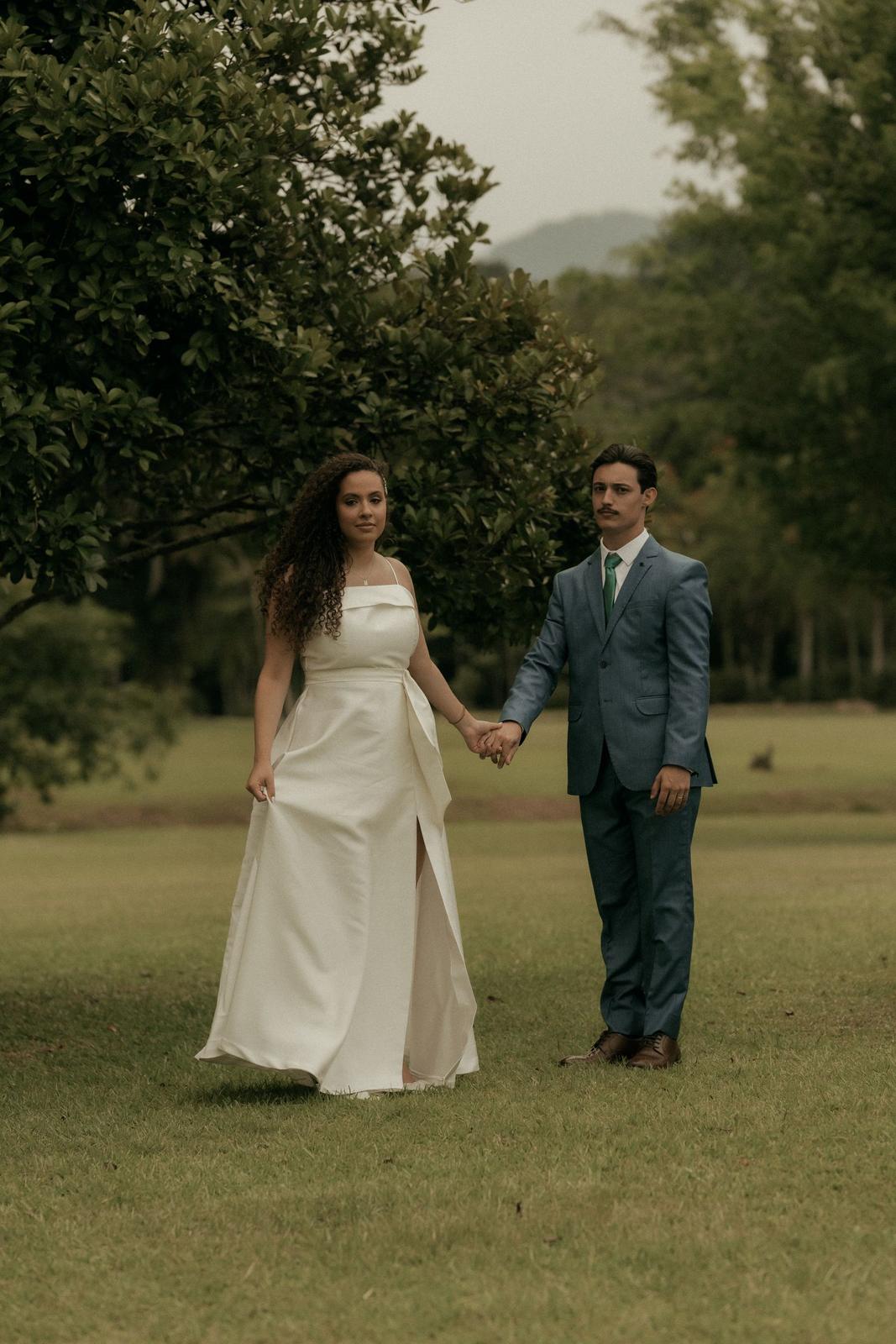 A bride and groom walking hand in hand on a lawn