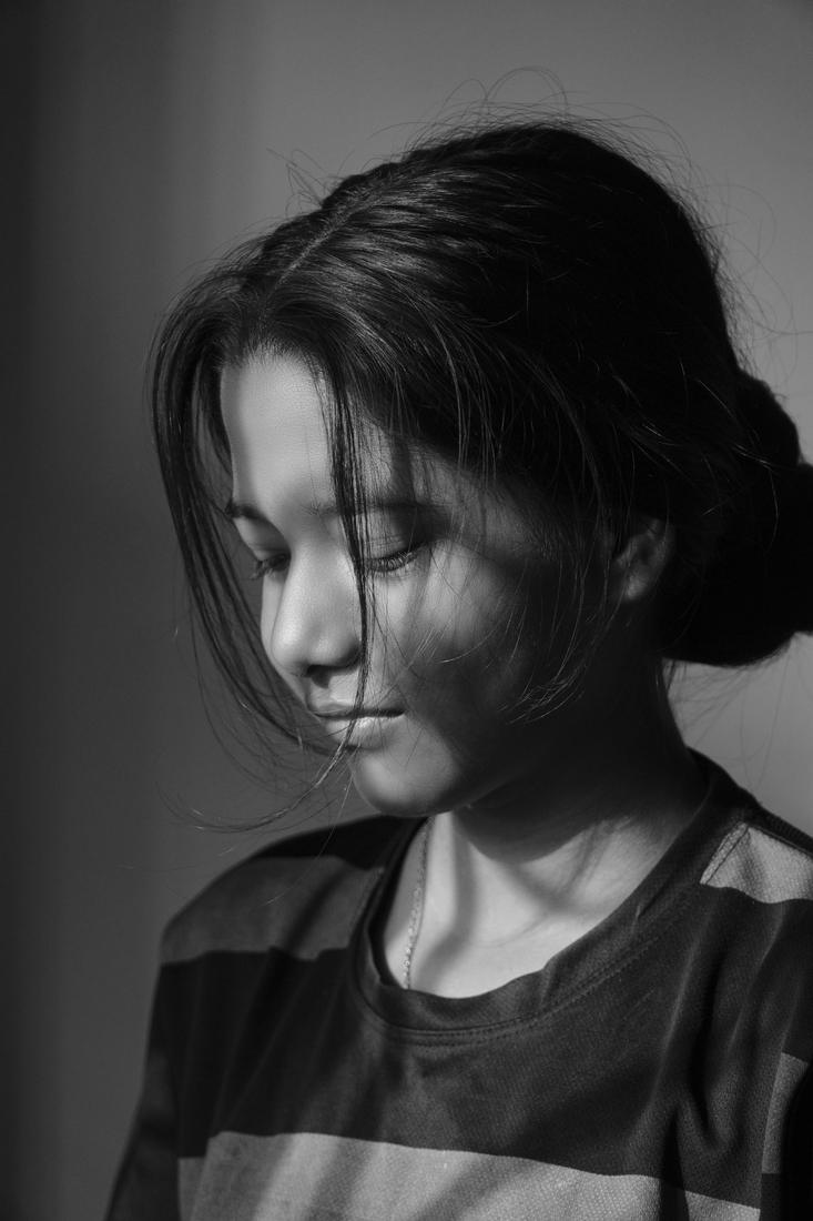 A black and white portrait of a woman looking down