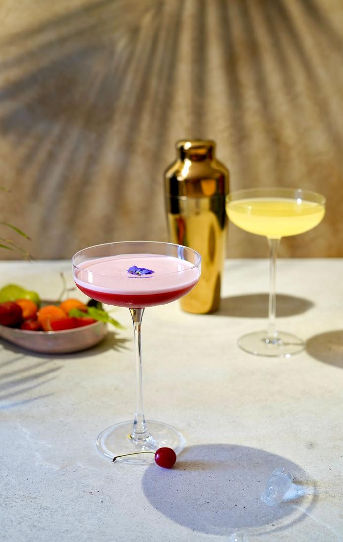 A pink cocktail and a pale cocktail on a table