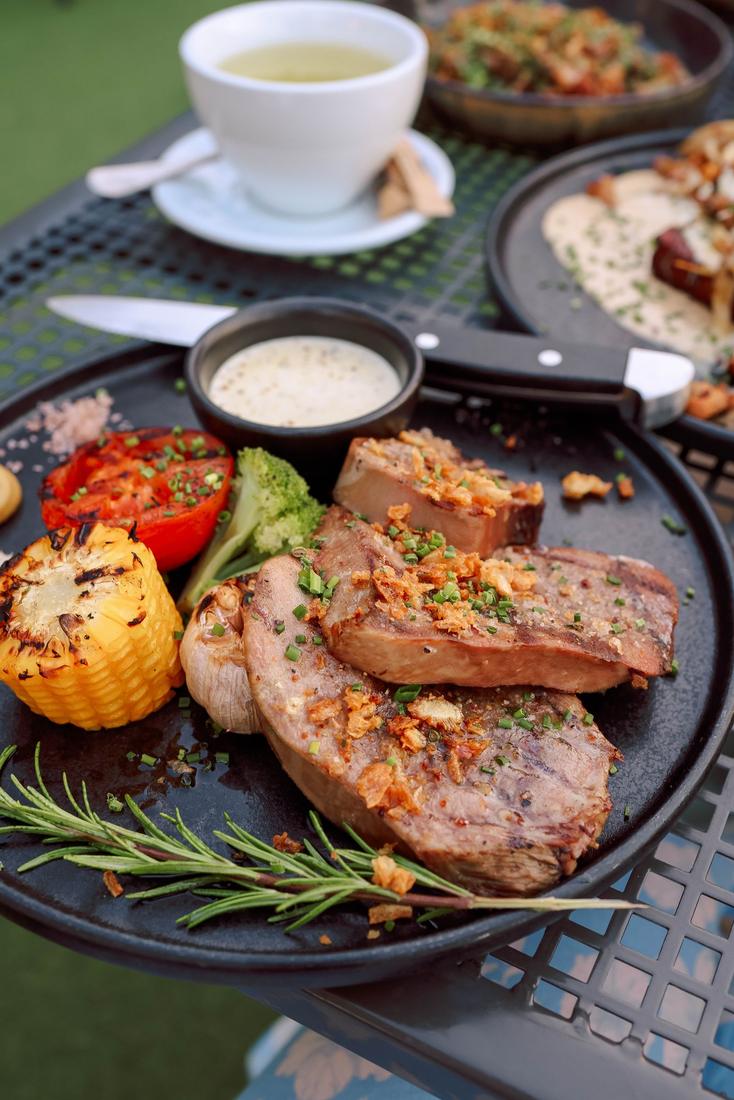 Grilled meat with charred corn and tomato on a board