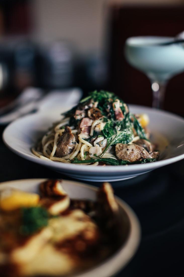 A bowl of pasta with greens and mushrooms
